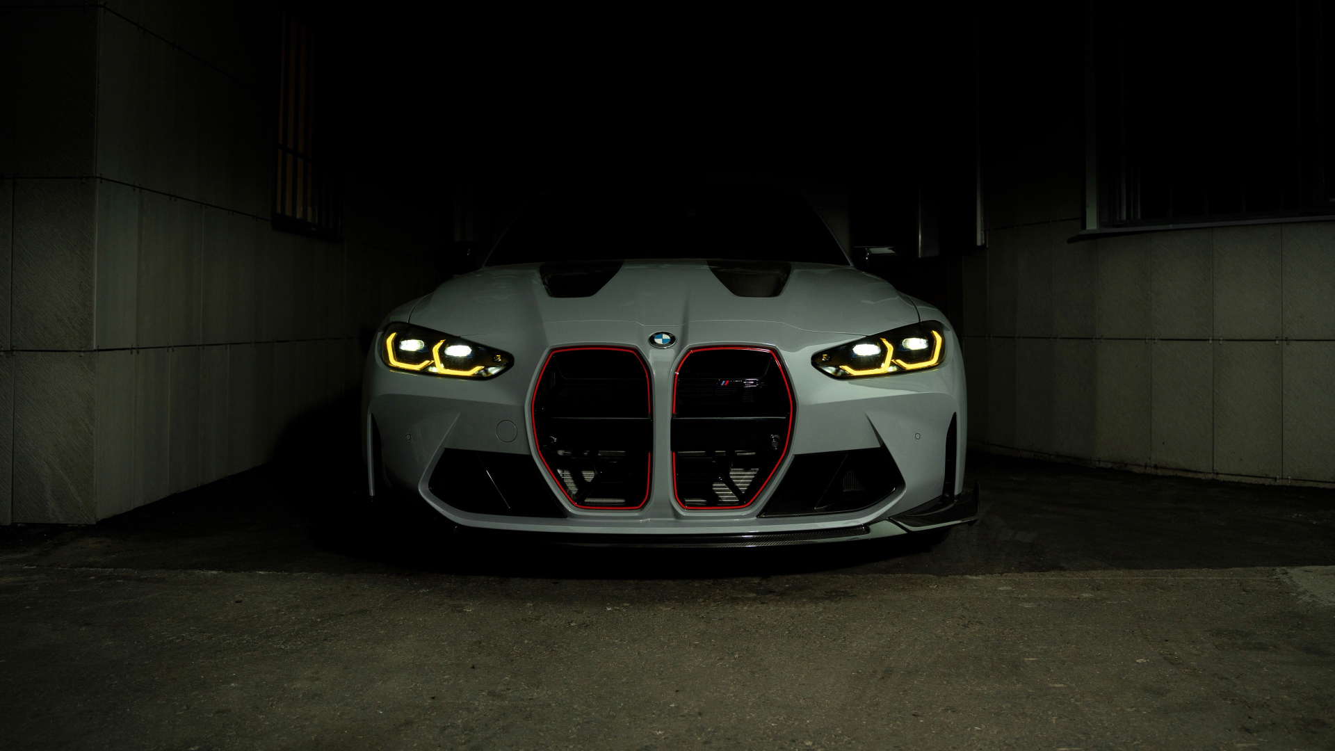 BMW M3 with glowing yellow headlights in a dark garage